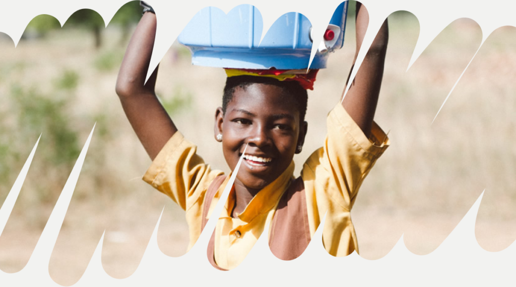 Criança, apoiada pela ONG Saha Global, carregando água em balde na cabeça